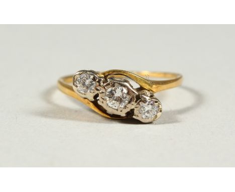 AN 18CT GOLD THREE STONE DIAMOND CROSSOVER RING.