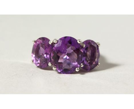 A SILVER THREE-STONE AMETHYST RING.