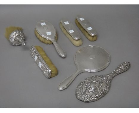 A silver mounted four piece dressing set, with engine turned decoration, comprising; a hand mirror, a hairbrush and two cloth
