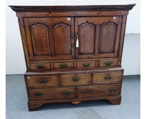 A mid-18th century inlaid oak bacon cupboard, the pair of double arch panel doors over five drawers on bracket feet, 137cm wi
