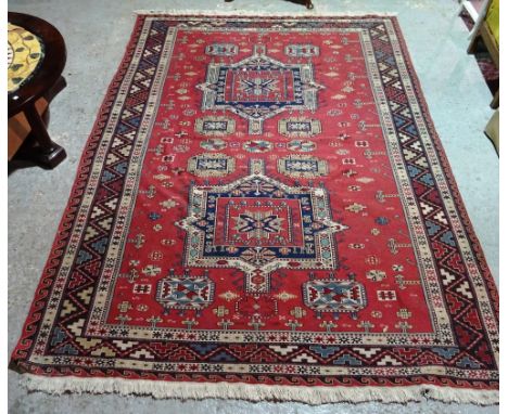 A Soumac carpet, Caucasian, the madder field with two medallions, minor motifs, a brown waved vine border, 260cm x 195cm.