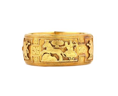 A gold oval hinged bangle, the front decorated with ancient Egyptian style figures, including a central chariot, otherwise wi