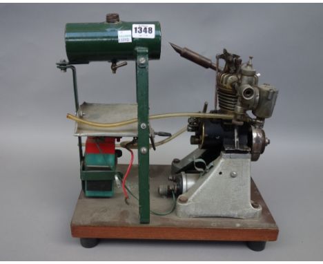 A small petrol engine by 'Amal', Birmingham, with fuel reservoir, battery and fly wheel, on a wooden plinth, 31cm wide, (a.f)