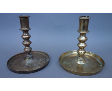 An 18th century bell metal brass candlestick of turned form, on a wide plan circular base, and another later similar candlest