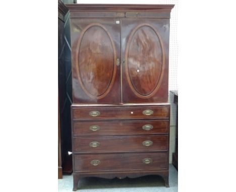 A George III inlaid mahogany linen press, the pair of oval panel doors over four long graduated drawers, on splayed bracket f