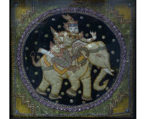 A FRAMED AND GLAZED INDIAN SEQUIN AND METAL THREAD EMBROIDERED STAMP-WORK TEXTILE PANEL of a deity on the back of an elephant