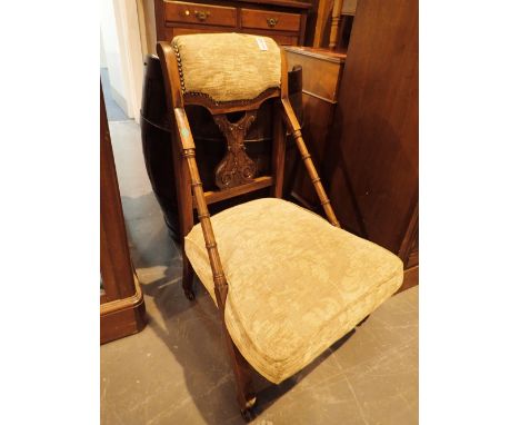 Victorian low upholstered chair with bamboo arms and carved backsplat on ceramic castors