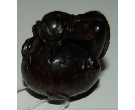 A 20thC carved wood Japanese netsuke, a study of a grotesque bird like creature hatching out of an egg with inscribed charact