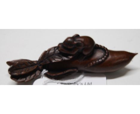A 20thC carved wood japanese netsuke, a study of a rat feeding upon a large elongated fruit , with inscribed character marks.