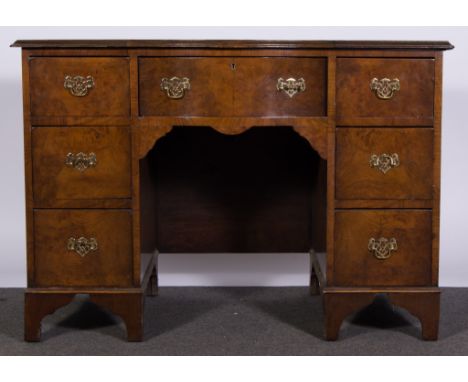 A mahogany serpentine fronted twin pedestal desk, with central drawer and three drawers to each side, bracket feet and leathe