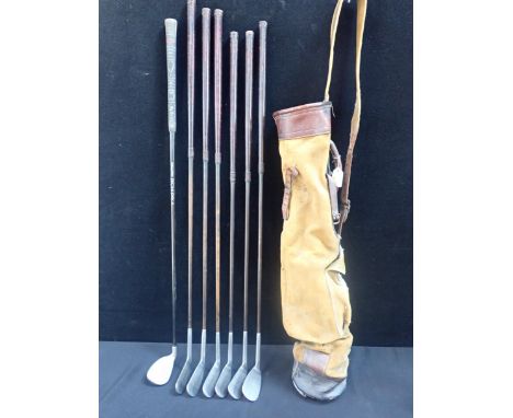 AN OLD GOLF BAG WITH SEVEN VINTAGE IRONS 