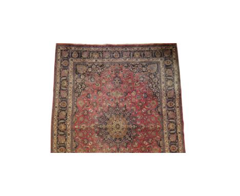 PERSIAN CARPET of Tabriz design, the central red ground rectangular panel with an ivory and multi-coloured floral medallion, 