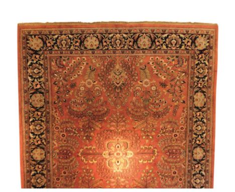 A PERSIAN SMALL CARPET with all over foliate decoration on a salmon pink ground within a dark blue border, 310cm x 244cm