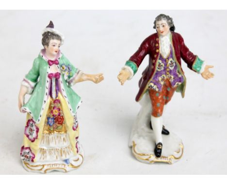 Two ceramic figures of a lady and gentleman in elaborate dress with painted and gilt detail, both with gilt anchor-type marks