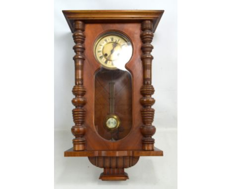 A late 19th/early 20th century walnut Vienna style eight day wall clock, the dial set with Roman numerals, with a glazed door