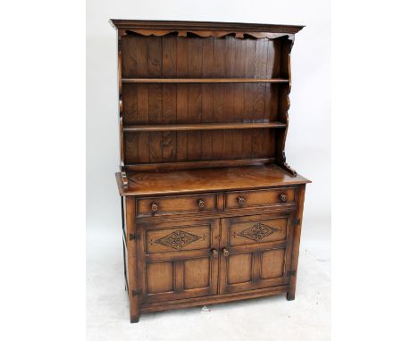 An oak dresser with two shelves above two short drawers and twin cupboard doors with carved lozenges enclosing single shelf, 