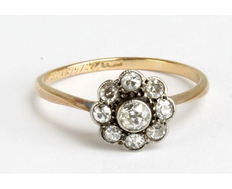 A yellow metal and diamond daisy cluster ring set with nine old cut stones, rubbed mark and presentation inscription to band 