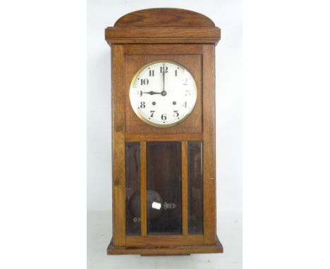 An early 20th century oak cased eight day wall clock, the silvered dial with Arabic numerals, length 76cm.