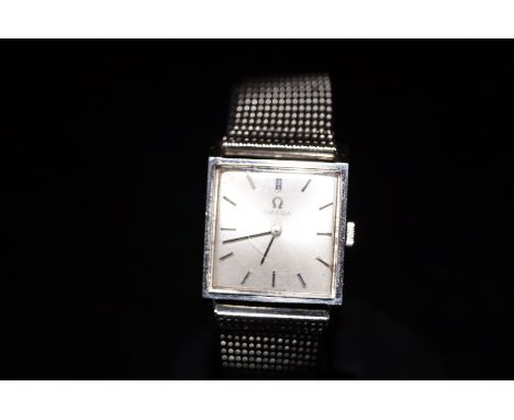 Omega ladies wristwatch dated 1964. Soft white metal strap with the manual wind movement set in a square case. Currently tick