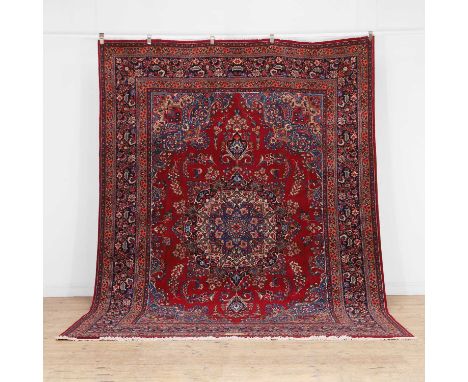 A Tabriz carpet, signed, with a central blue medallion, to a red field, and navy border,339 x 243cm