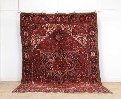 A Heriz wool carpet, Persian, with central medallion to red ground, with navy borders, 324 x 244cm