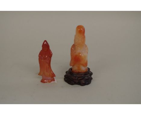 Two Chinese agate or red jade figures, comprising: a sage, 9cm high, on fitted hardwood stand; and Guanyin, 8.5cm high. (2) 
