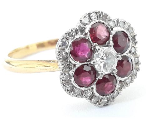 A diamond and ruby coloured stone cluster ring, the flower head measuring 18mm x 17mm, band indistinctly marked, gross weight