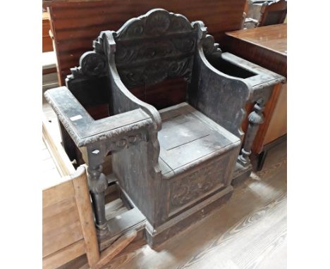 A carved oak hall stand with central lift top seat and stick stand compartments either side, height 103cm, width 110cm, depth