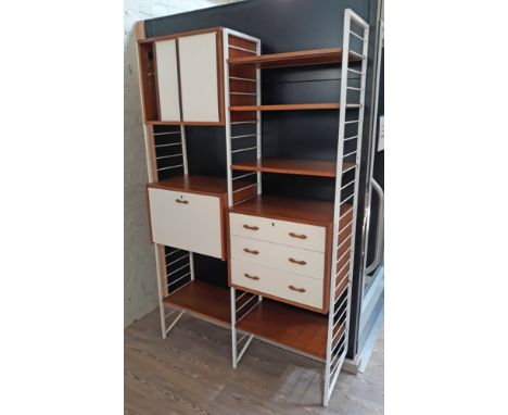 A Staples Ladderax modular shelving unit comprising three white ladder supports, five shelves, a drop front cabinet, a chest 