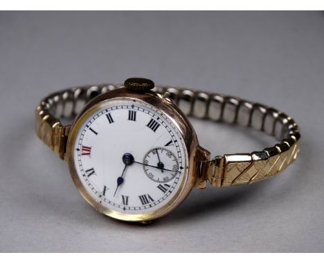 An early 20th century ladies yellow gold cased wristwatch - 9ct, the white enamel dial set out in Roman numerals with a subsi