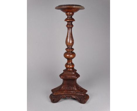 A 19th century oak baroque style candlestick - the dish on a turned support and triform base with scroll feet, height 26cm