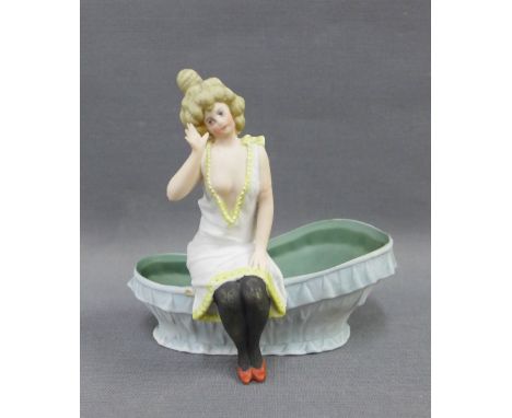 Continental bisque figure of a lady, modelled seated on the edge of a bath tub, 12cm high 