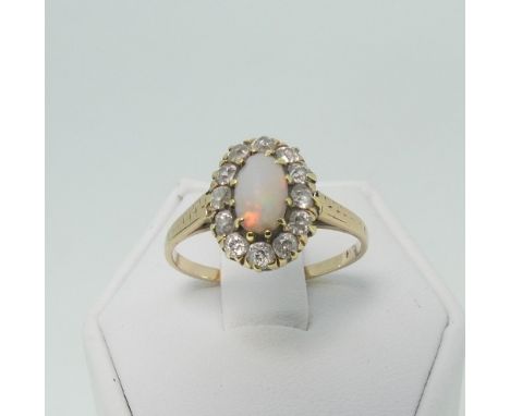 An opal and diamond oval Cluster Ring, the opal surrounded by twelve small diamonds and all mounted in unmarked yellow metal,