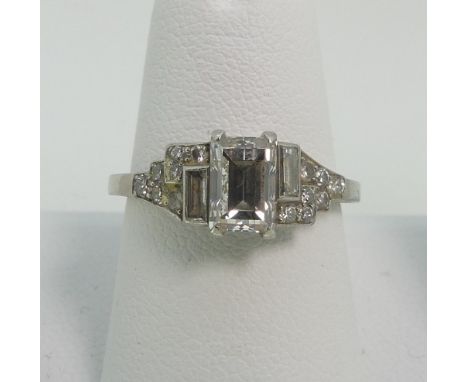 An Art Deco style diamond Dress Ring, the front vertically off set with three baguette diamonds, the shoulders with seven sma