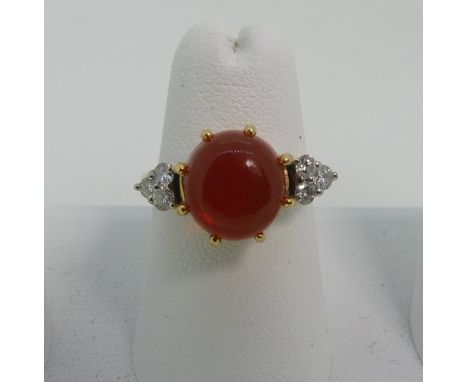 A fire opal and diamond Ring, the central circular cabochon opal approx 9mm diameter, with three diamonds on each shoulder, a