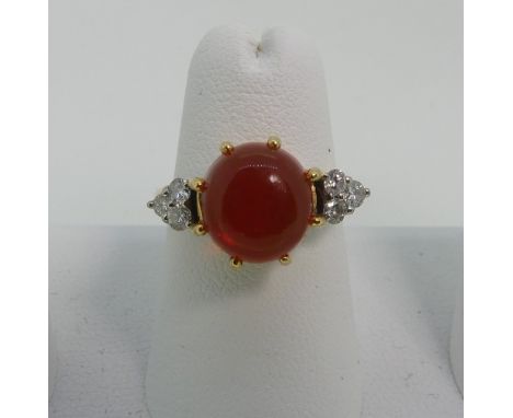 A fire opal and diamond Ring, the central circular cabochon opal approx 9mm diameter, with three diamonds on each shoulder, a