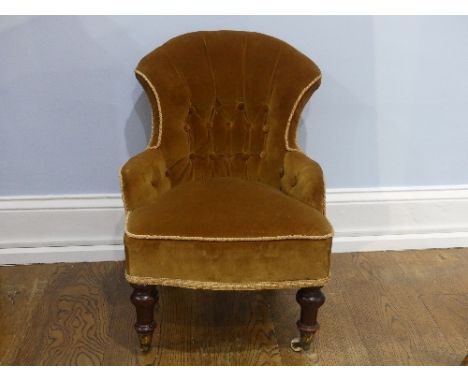 An antique button back Child's Chair, in mustard upholstery, on turned legs, brass caps and castors, 18in (45cm) wide x 21in 