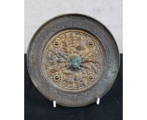 A 19th century Chinese cast brass circular mirror, embossed with various objects within a scroll work border. H.16 W.16cm D.1