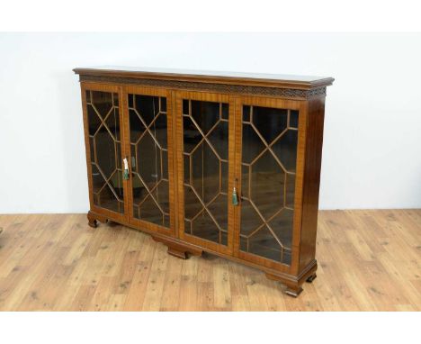 A 1920's mahogany glazed bookcase, with blind fretwork to the frieze, two double astragal glazed cabinets enclosing shelves, 