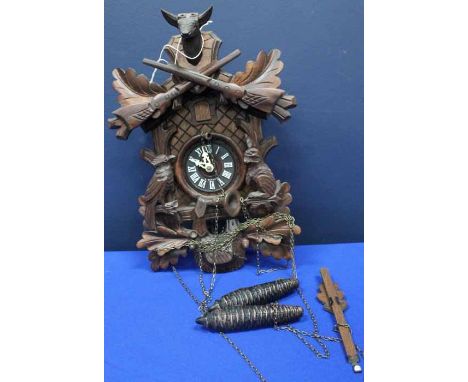 20TH CENTURY CARVED CUCKOO CLOCK
in the black forest style, with a carved hare and jay topped with a pair of rifles and a dee