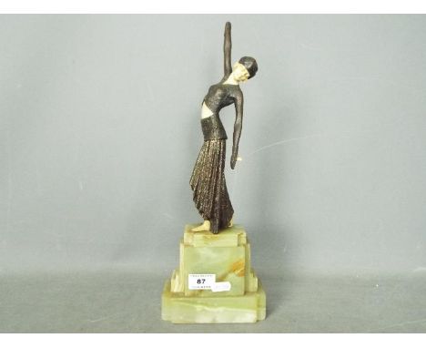 An Art Deco sculpture depicting a stylish lady in bronze with ivorine or bakelite face, feet and midriff (loss to the hands),