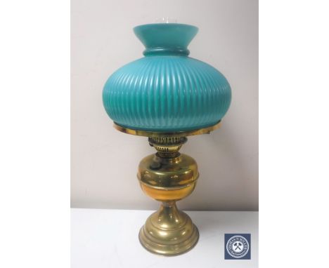An early 20th century brass oil lamp with chimney and green glass shade 
