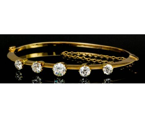 A late Victorian gold coloured metal mounted diamond set stiff bangle, the central old cut stone being approximately .75ct, b