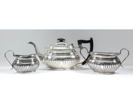 A George V harlequin silver rectangular three piece tea service with part reeded bodies, comprising - tea pot with ebonised a