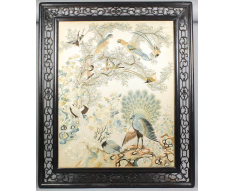 A Chinese Cantonese embroidered panel on silk worked in coloured silks with a pair of peacocks, and parrots and exotic birds 