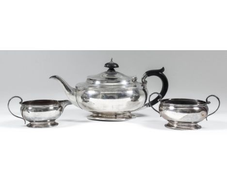 A George V silver oval three piece tea service of bulbous squat form with reeded rims and leaf cast scroll handles, comprisin