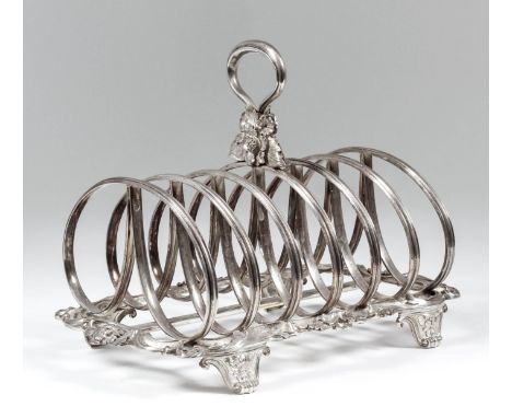 A William IV silver six division toast rack with moulded double-loop divisions, the loop handle with leaf and flowerhead orna