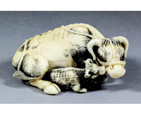 A Japanese carved ivory netsuke of a reclining water buffalo and calf, 0.75ins (1.8cm) high x 2.25ins (5.8cm) overall, signed