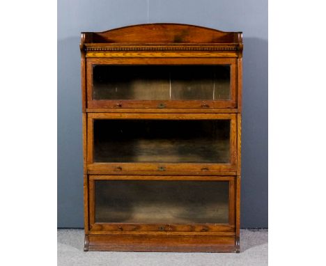 A Lebus oak three tier sectional bookcase with arched top and dentil moulded frieze, each tier with glazed rising fronts, on 