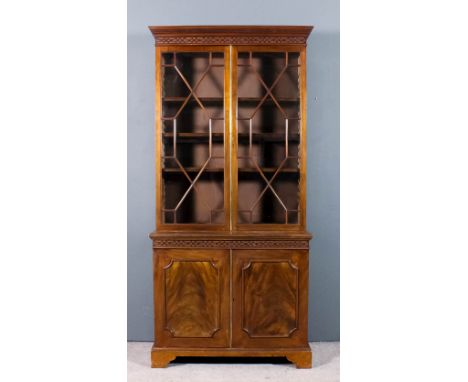 An Edwardian mahogany bookcase of "18th Century" design, the upper part with dentil moulded cornice and blind fret carved fri